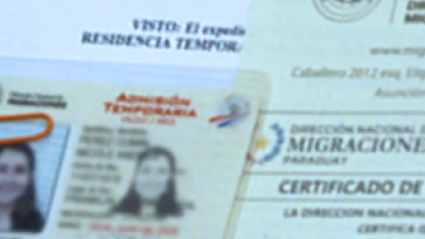 Close-up of a Paraguayan ADMISIÓN TEMPORARIA residency card alongside the Migraciones certificate that accompanies it