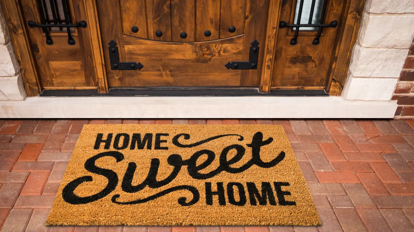 A 'Home Sweet Home' doormat at a wooden front door — the homecoming feeling at the end of the residency journey