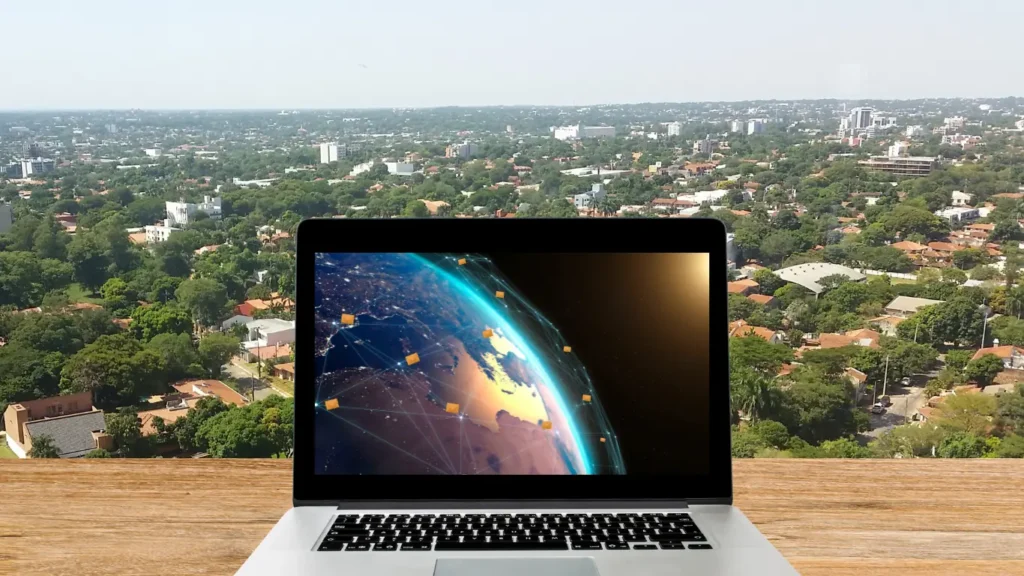 Laptop screen showing world map with mail icons moving globally, set against a backdrop view of the Asunción, Paraguay skyline, symbolizing managing Paraguayan virtual address from anywhere.