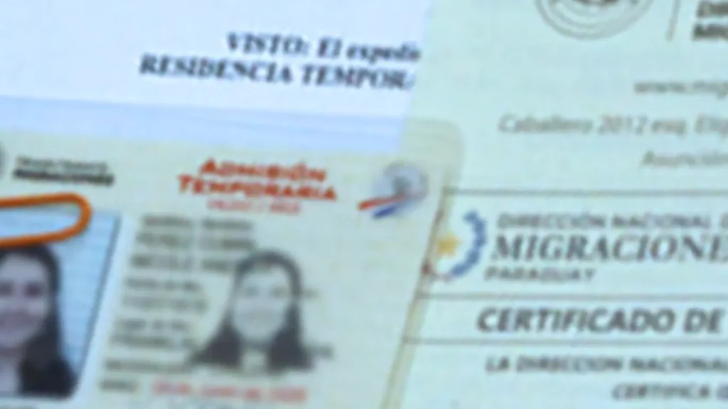 Blurred image of official residency paperwork with a focused, clear Paraguayan Temporary Residency Card on top.