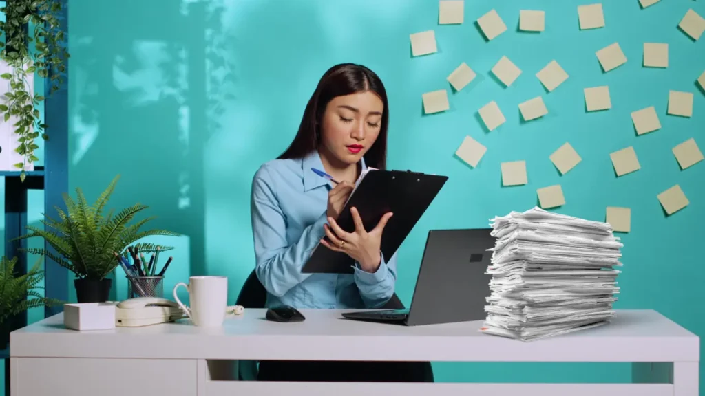 Woman at a desk reviewing papers and sticky notes, representing the planning and detailed requirements of the residency application process.